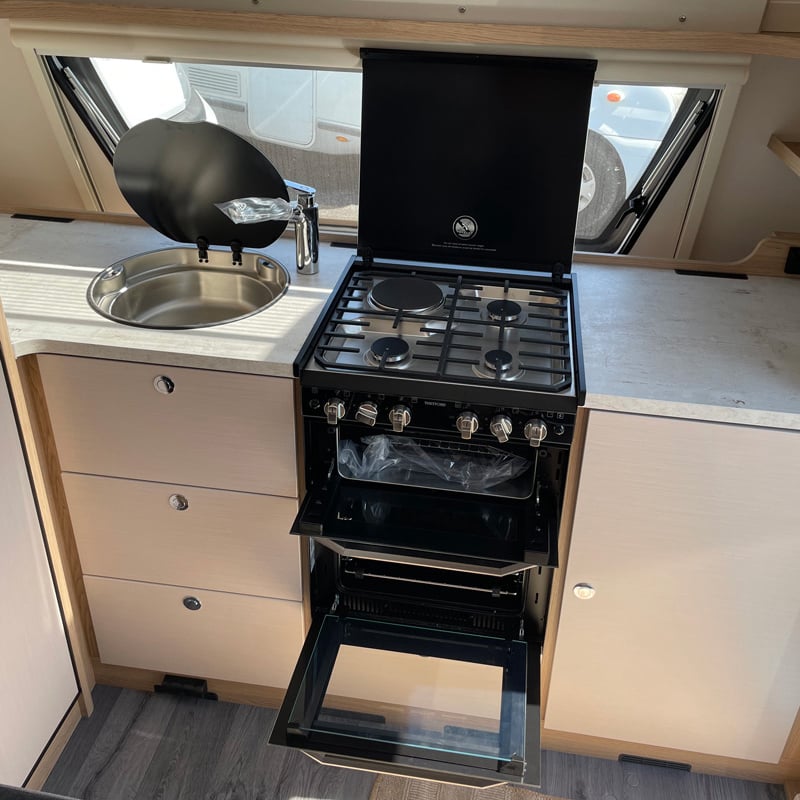 Caravane LMC VIVO 580 D espace cuisine avec plaque de protections ouvertes et four ouvert